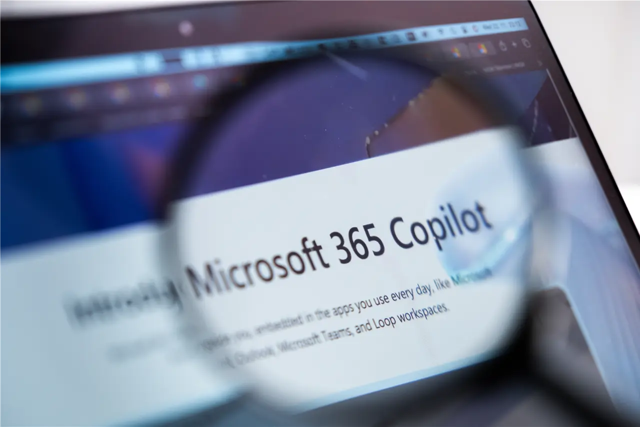 Diese Grafik zeigt den Bildschirm eines Laptops, auf dem „Microsoft 365 Copilot“ vergr&ouml;&szlig;ert durch eine Lupe zu sehen ist.