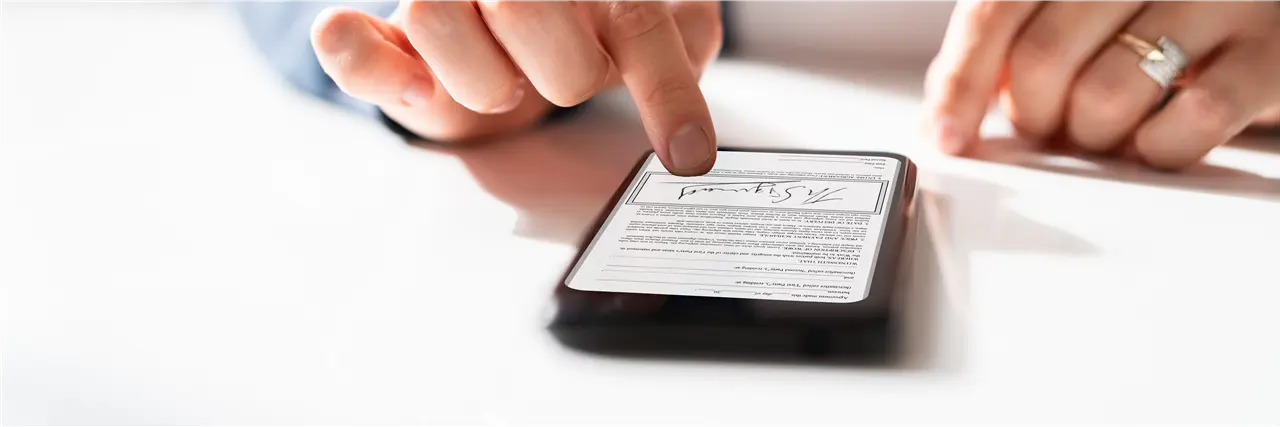 Ein Smartphone zeigt ein digitales Dokument mit Unterschrift, das von einer Hand bedient wird. Dieses Bild symbolisiert die digitale Dokumentenverwaltung.