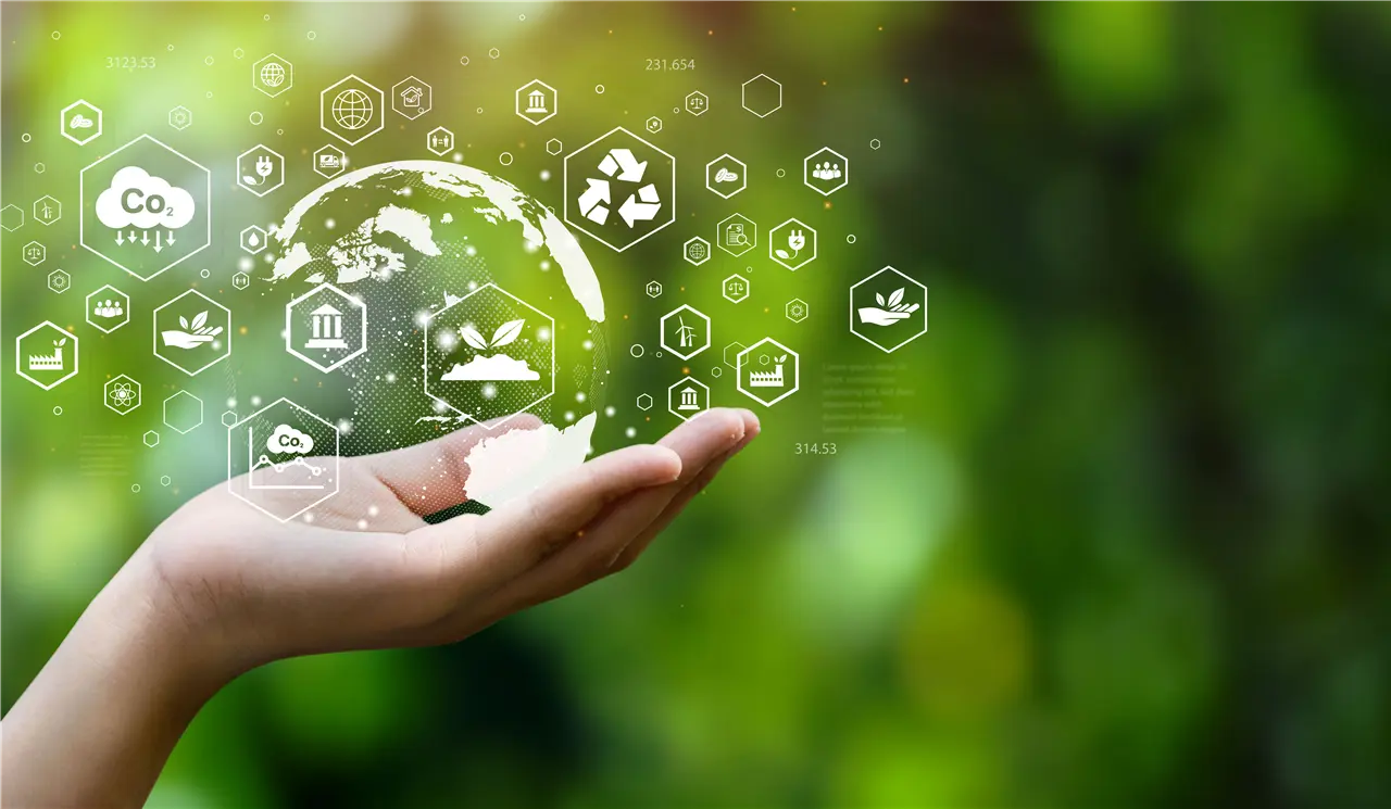 Ein Hand hält eine transparente Weltkugel, umgeben von Symbolen für Nachhaltigkeit und Umweltschutz, auf einem grünen, unscharfen Hintergrund. Die Symbole stellen Konzepte wie CO2-Reduzierung und erneuerbare Energien dar.